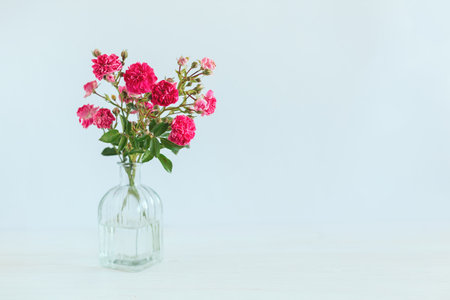 Romantic bouquet of pink roses in a glass vase on a white background. Place for text.の写真素材