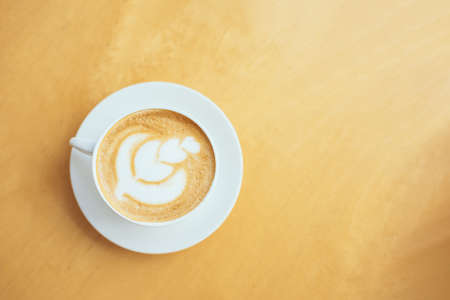 Cup of coffee with latte art on a wooden table in a cafe. Flat lay. Place for text.