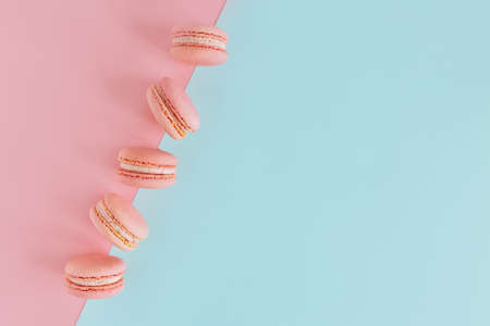 Tasty french pink macarons on a blue and pink pastel background. Place for text. Flat lay.の写真素材
