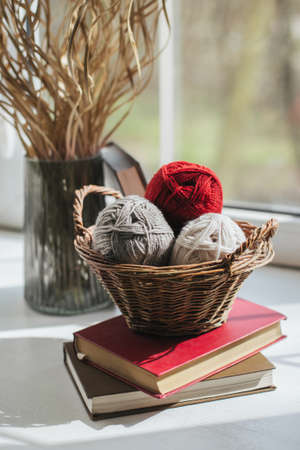Cozy balls of yarn for hand knitting in the basket near the window. Background for handmade and slow...