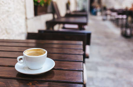 Cup of coffee on a rustic wooden table in a street cafe. Place for text.の写真素材