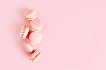 Tasty french macarons on a pink pastel background. Place for text.