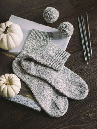 Hand knitting socks with needles and yarn balls on a dark wooden background. Concept for handmade...