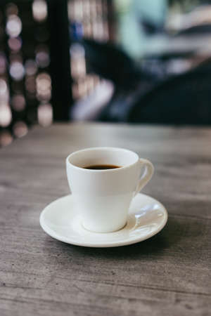 Cup of black coffee on a rustic wooden table in a street cafe. Place for text.