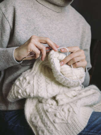 Woman with hand knitting, needles and yarn on a dark background. Concept for handmade and hygge slow life.の写真素材