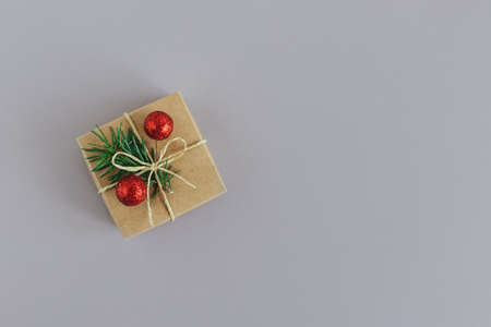 Craft gift box with spruce branch and red balls on a gray background. Holiday eco-friendly concept. Place for text. Flat lay.の写真素材