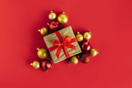 Gift box with red and golden balls on a red background. Holiday concept. Place for text. Flat lay.の写真素材