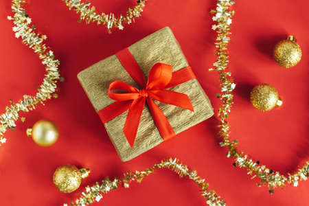 Golden gift box with christmas ornaments on a red background. Holiday concept. Place for text. Flat lay.の写真素材