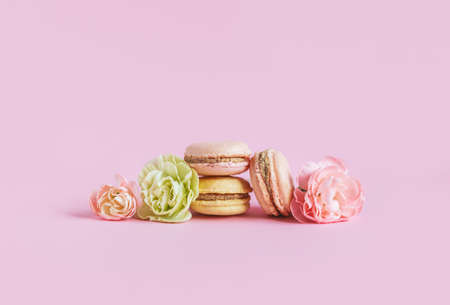 Tasty french macaroons with flowers on a pink pastel background. Place for text.の写真素材
