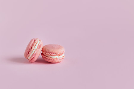 Tasty french macaroons with flowers on a pink pastel background. Place for text.の写真素材