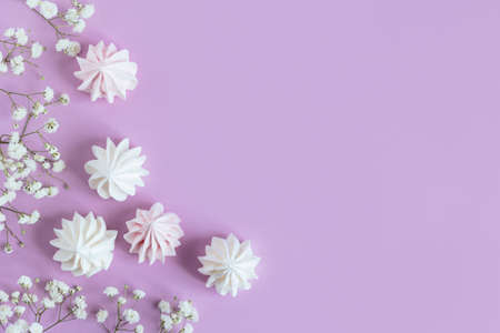 White marshmallows and flowers on a violet pastel background. flat lay. Place for text.の写真素材