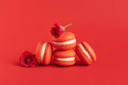 Red french macarons with rose flower on a red background. Place for text.の写真素材