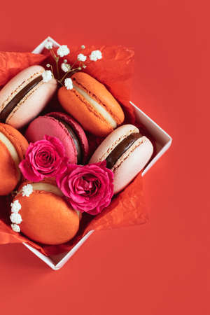 Tasty french macarons in a box on a red background. Concept for Valentine's day. Place for text. flat lay.の写真素材