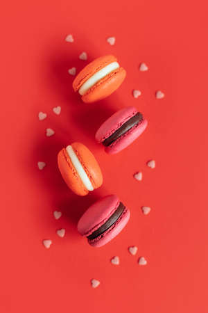 Tasty french macarons on a red background. Concept for Valentine's day. Place for text. flat lay.