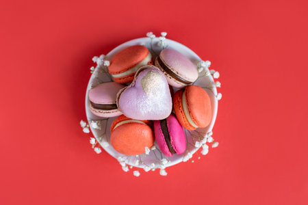 Tasty french macarons with flowers on a red background. Place for text. flat lay.の写真素材