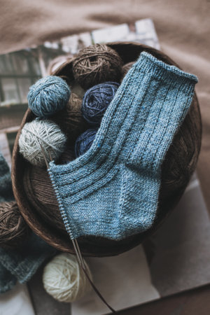 Hand knitted socks with needles and yarn ball in a basket. Concept for handmade and hygge slow life.