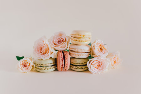 Tasty french macarons with tender rose flowers on a peach pastel background. Place for text.の写真素材