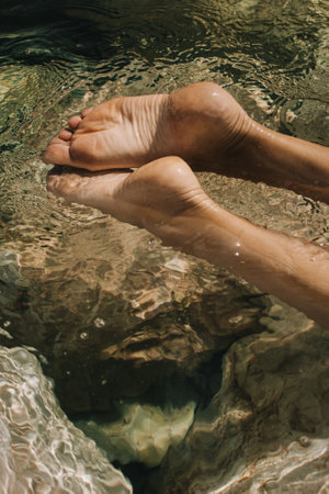 Women's feet in the sea. Close-up top view of a young woman's bare feet in a water.