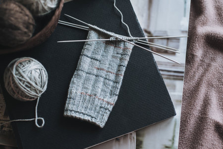 Hand knitted socks with needles and yarn ball in a basket. Concept for handmade and hygge slow life.