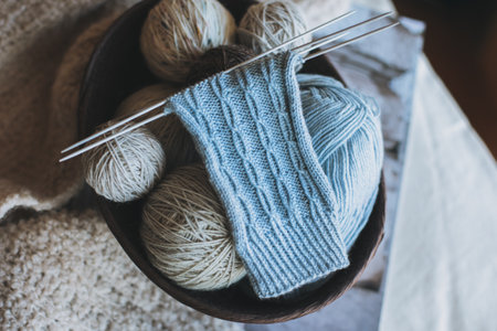 Hand knitted socks with needles and yarn ball in a basket. Concept for handmade and hygge slow life.の写真素材