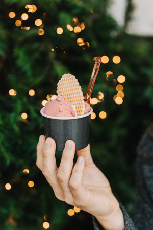 Delicious ice cream with waffle biscuit in a cap in a woman's hand. Close-up.の写真素材