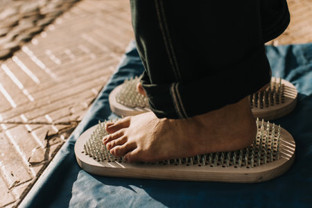Feet standing on a Sadhu board (Yoga board) with sharp nails outdoor. Practice yoga, meditation, concentration. Close-up.の写真素材