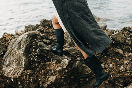 Girl in rubber boots on the rocks by the sea. Selective focus.の写真素材
