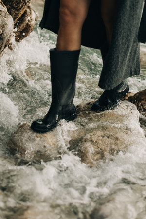 Girl in rubber boots on the rocks by the sea. Selective focus.の写真素材