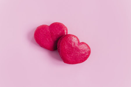 Pink heart shaped French macarons on a pink pastel background. Concept for Valentine's day. Place for text.の写真素材