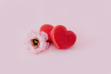 Pink heart shaped French macarons with flower on a pink pastel background. Concept for Valentine's day. Place for textの写真素材