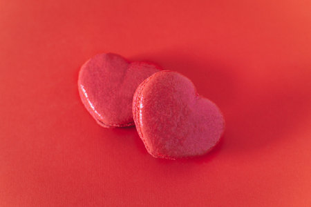 Pink heart shaped French macarons on a red background. Concept for Valentine's day. Place for text.の写真素材