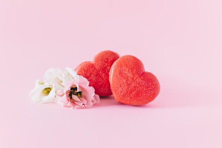 Pink heart shaped French macarons with flower on a pink pastel background. Concept for Valentine's day. Place for textの写真素材