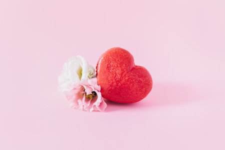 Pink heart shaped French macaron with flower on a pink pastel background. Concept for Valentine's day. Place for textの写真素材