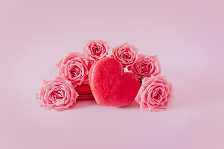 Pink heart shaped French macarons with rose flowers on a pink pastel background. Concept for Valentine's day. Place for textの写真素材
