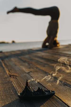 Girl practicing yoga and meditating on the beach at sunset. Selective focus.の写真素材
