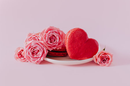 Pink heart shaped French macarons with rose flowers on a pink pastel background. Concept for Valentine's day. Place for textの写真素材