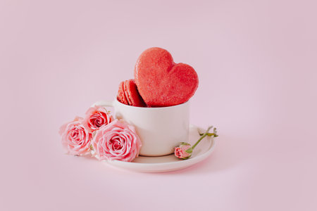 Pink heart shaped French macarons with rose flowers on a pink pastel background. Concept for Valentine's day. Place for text.の写真素材