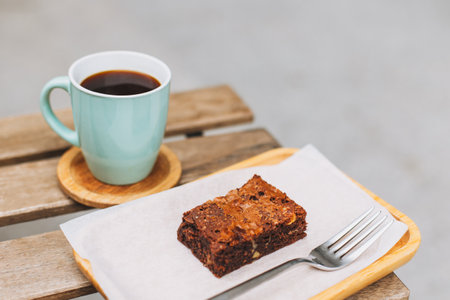 Cup of black coffee and a brownie cake on a table in a street cafe. Place for text.の写真素材