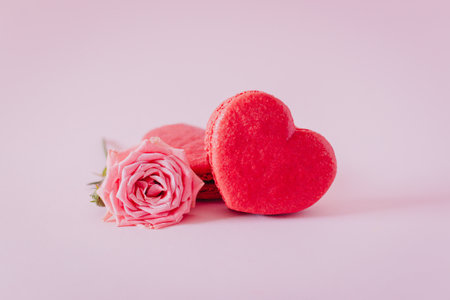 Pink heart shaped French macarons with rose flowers on a pink pastel background. Concept for Valentine's day. Place for text.の写真素材