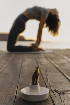 Girl practicing yoga and meditating on the beach at sunset. Selective focus.の写真素材