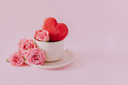 Pink heart shaped French macarons with rose flowers on a pink pastel background. Concept for Valentine's day. Place for text.の写真素材