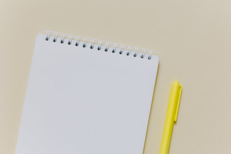 Notebook with blank page and yellow pen on light yellow background. Flat lay. Place for text.の写真素材