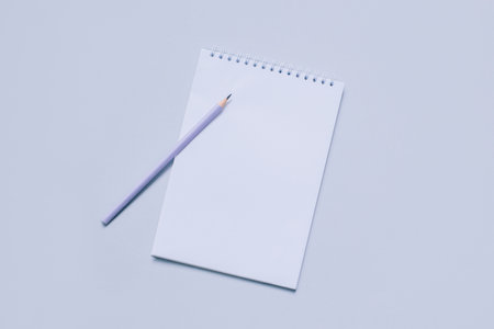 Notebook with blank page and pencil on light purple background. Flat lay. Place for text.の写真素材