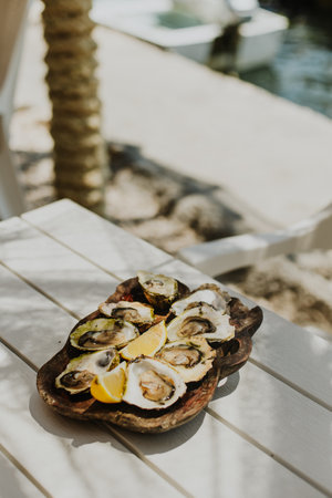 Delicious oysters with lemon on a wooden plate in restaurant by the sea. Close up.の写真素材