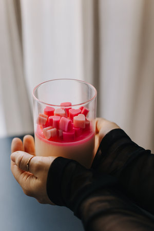 Female hands holding a candle with small pink hearts. Close up. Place for text.の写真素材