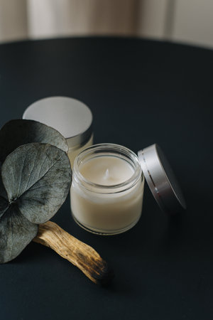 Tender white aroma candle and palo santo stick on a black table. Cozy modern home atmosphere.の写真素材