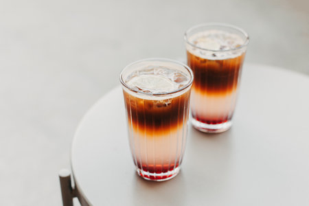 Two glasses of refreshing summer cocktail with lemon and ice on a table. Cocktail with ice, coffee and lemon slices. Place for text.の写真素材