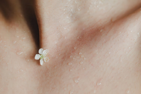 Close up cherry blossom flower on a dew female skin with water drops. Concept for purity, freshness and clean skin. Minimal concept.の写真素材