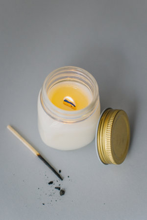 Tender white aroma candle with match on a gray background. Modern minimalism.の写真素材