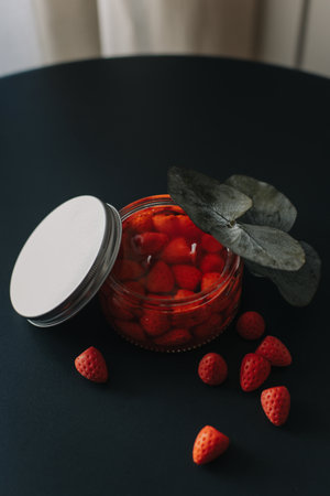 Tender aroma candle decorated with berries on a black table. Cozy modern home atmosphere. Selective focus.の写真素材
